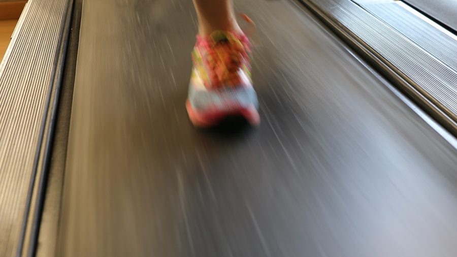 Running shoes closeup of athlete runner training. Woman feet in colorful shoes running on treadmill machine indoor. Fitness center training. Healthy lifestyle concept.